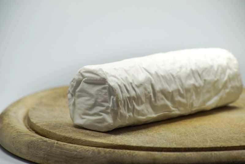 Rollo de queso de cabra fresco sobre una tabla de madera.