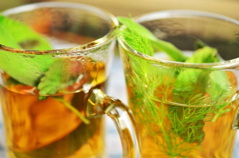 Dos tazas de vidrio con infusión y hojas de menta.
